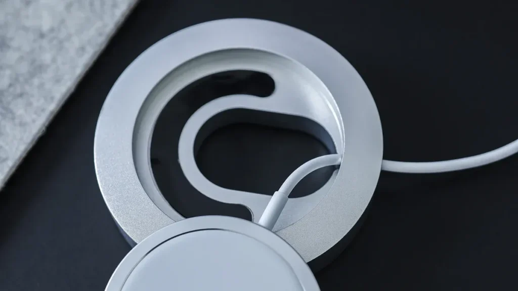 Close - up of a silver MagSafe magnetic charging accessory with a cable, showcasing the MagSafe magnets' structure.