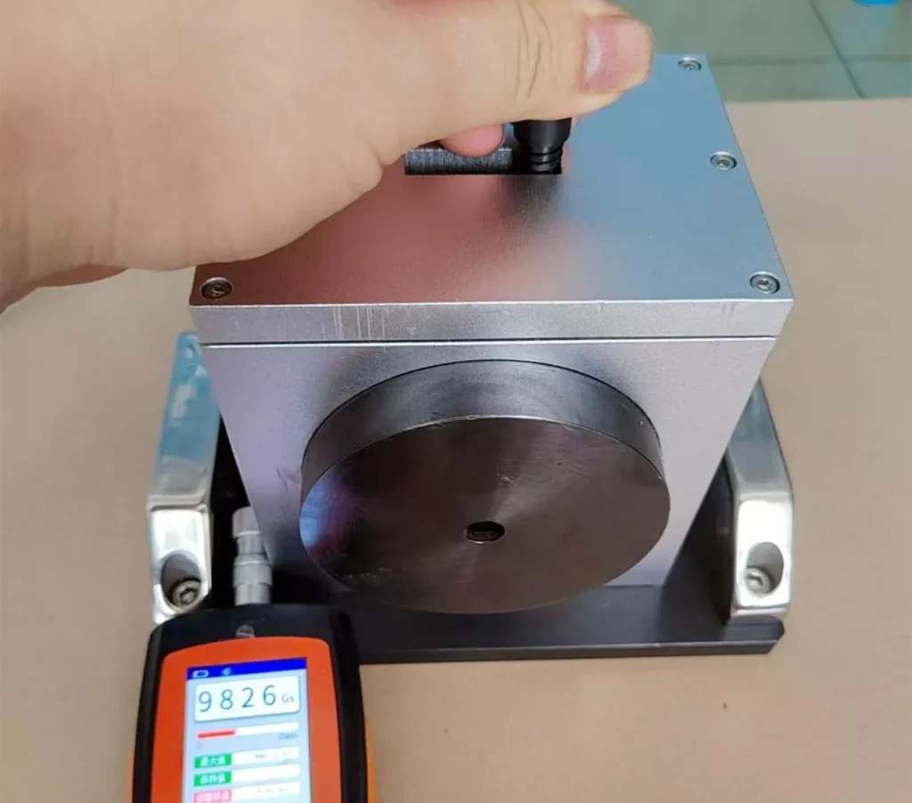A hand testing the gauss strength of a magnet with a precision device, showing the measurement of magnetic performance.