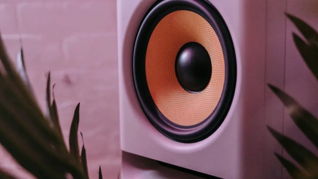 Close - up of a speaker using alnico magnet with a pink background, showing the speaker cone and enclosure.