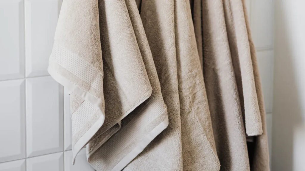Beige towels hanging on a magnetic hook system against a tiled wall, demonstrating Magnetic Hooks’ use in home organization.