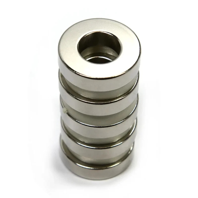 Closeup of single tiny neodymium magnet ring, highlighting Ni - Cu - Ni coating and +/-0.05mm tolerance for precision applications.
