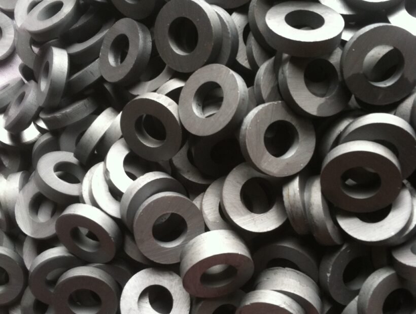 Large pile of circular ring - shaped ferrite magnets, showcasing their common industrial form